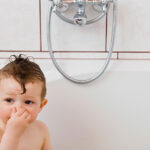 San Leandro plumbers and smelly drains blog featured image showing baby holding nose in bath tub.